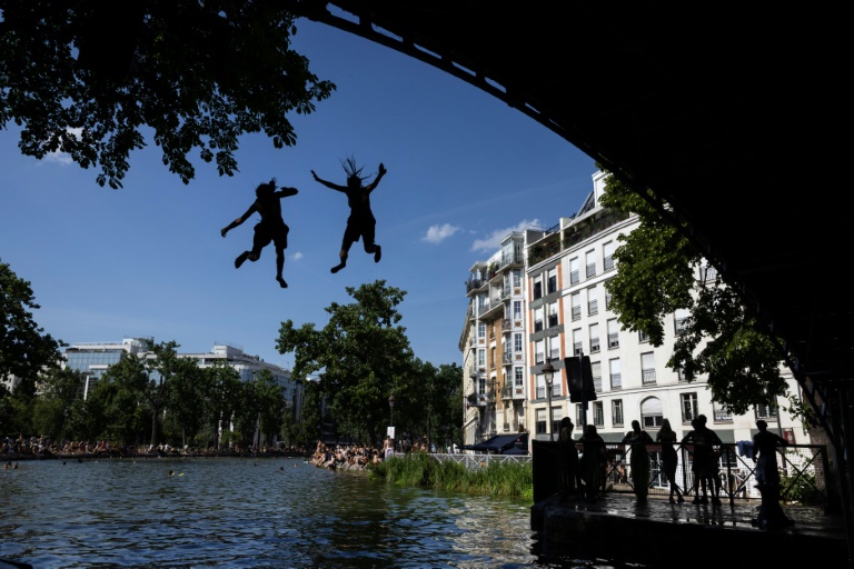 Des jeunes sautent d'un pont dans le canal Saint-Martin lors d'une vague de chaleur à Paris, le 22 juin 2026