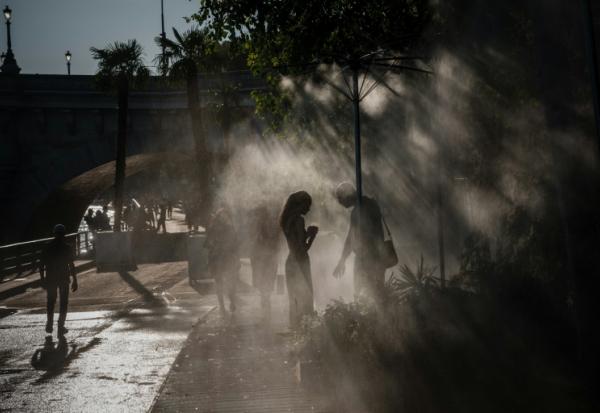 Des personnes se rafraîchissent sous des brumisateurs à Paris, le 10 juillet 2026