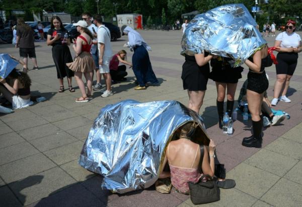 Des spectateurs se protègent de la chaleur  avec des couvertures de survie avant un concert de Bruo Mars à l'Olympic stadium de Berlin, le 28 juin 2026 en Allemagne