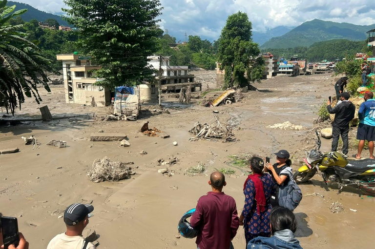 Des habitants observent des maisons partiellement submergées dans des eaux boueuses à la suite d'inondations soudaines survenues à Trishuli Bazar, dans le district de Nuwakot au Népal, le 26 août 2026.