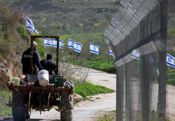 Des agriculteurs palestiniens sur leur tracteur passent près d'un grillage installé par des colons israéliens dans le village de Burqa, près de Naplouse, dans le nord de la Cisjordanie occupée, le 15 février 2026