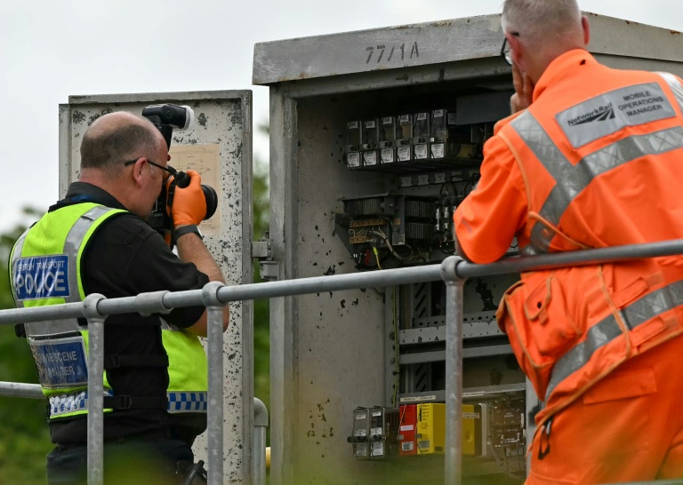 Un membre de la police des transports britannique photographie l'intérieur d'un boîtier de localisation (LOC) en bordure de voie, près du site d'une collision entre deux trains de l'East Midlands Railway (EMR) survenue la veille, le 20 juin 2026 au sud de Bedford, dans le centre de l'Angleterre