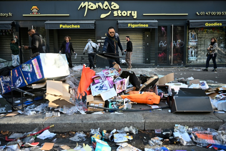 Un commerçant déblaie les débris devant sa boutique vandalisée au lendemain d'une manifestation contre la vie chère, le 18 octobre 2026 à Paris