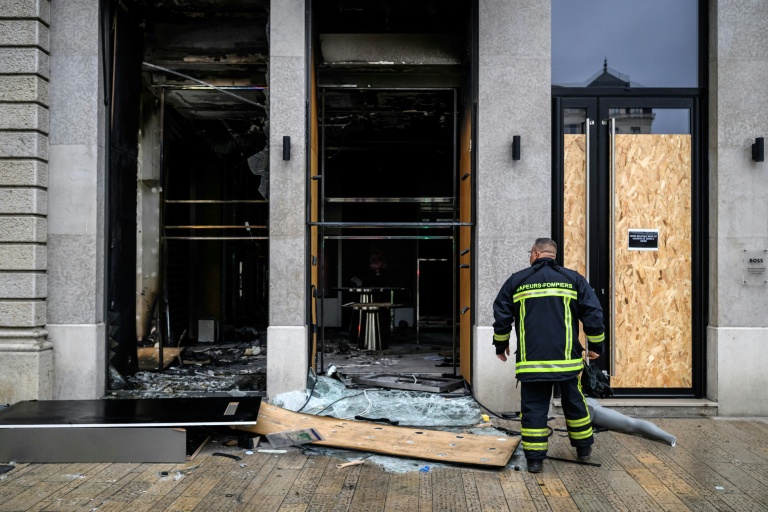 Un pompier devant les vitrines brisées d'un commerce, pillé et vandalisé, au lendemain d'une manifestation contre la vie chère à Lyon, le 18 octobre 2026