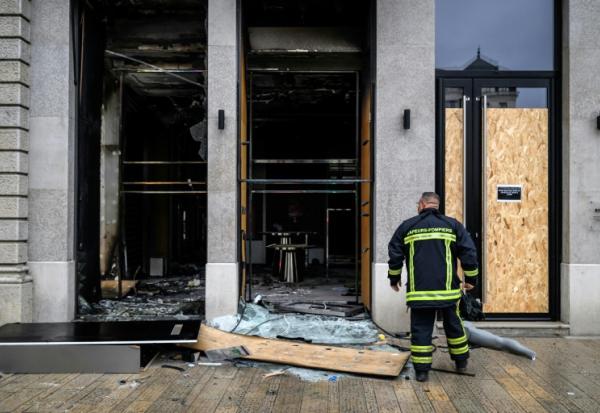 Un pompier devant les vitrines brisées d'un commerce, pillé et vandalisé, au lendemain d'une manifestation contre la vie chère à Lyon, le 18 octobre 2026