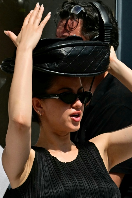 A guest protects herself from the sun with her purse before the Thom Browne collection show at Milan's Fashion Week Menswear Spring/Summer 2027, in Milan on June 22, 2026