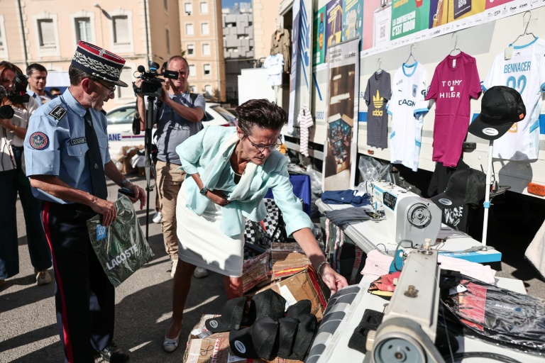 Corinne Simon (au centre), déléguée du préfet de police des Bouches-du-Rhône, examine des produits contrefaits lors de leur présentation avant leur destruction à Marseille, dans le sud-est de la France, le 18 juin 2026