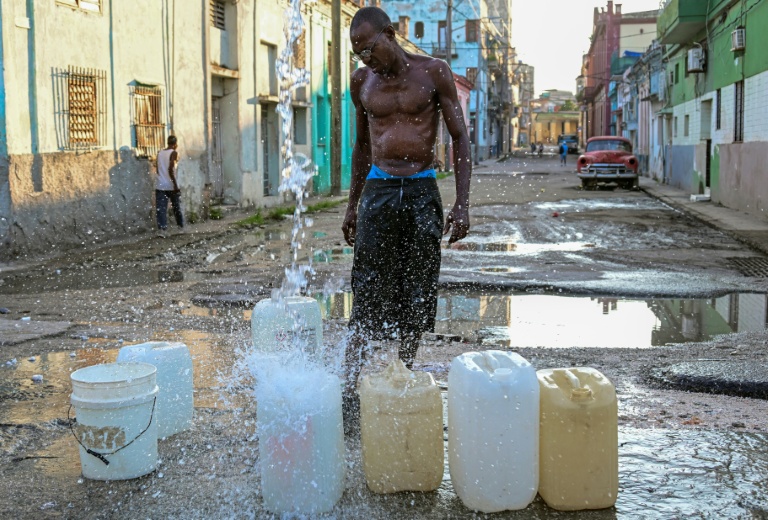 Un homme collecte de l'eau potable à un point de ravitaillement public dans une rue de La Havane, le 6 octobre 2026
