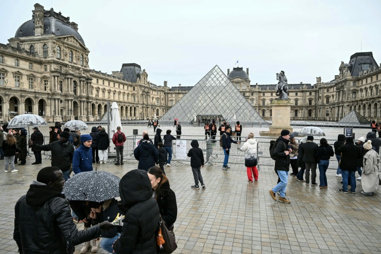 Des touristes  près des barrières bloquant l'accès à la pyramide du Louvre, conçue par l'architecte sino-américain Ieoh Ming Pei, et au musée du Louvre, le 12 janvier 2026 à Paris
