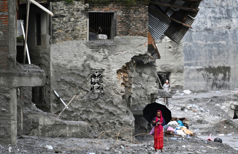 Une femme marche au milieu des ruines laissées par des crues soudaines dans le district de Nuwakot, au Népal, le 1er septembre 2026