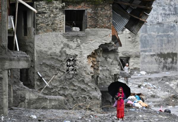 Une femme marche au milieu des ruines laissées par des crues soudaines dans le district de Nuwakot, au Népal, le 1er septembre 2026