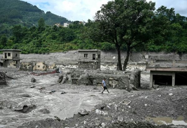 Un homme marche au milieu des décombres après la crue destructrice dans l'Himalaya, le 30 août 2026 à Trishuli, dans le district népalais de Nuwakot 
