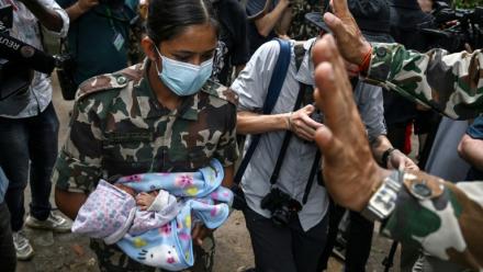 Une militaire porte un enfant secouru après la crue destructrice qui a fait au moins 633 morts à la frontière entre le Népal et la Chine, le 29 août 2026 au camp de Trishuli, dans le district népalais de Nuwakot  