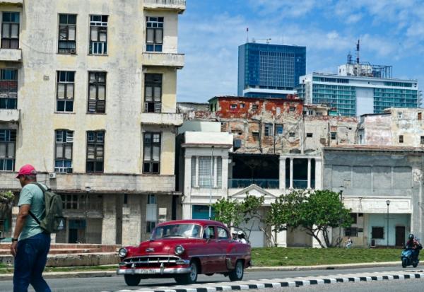 Un homme marche dans la rue tandis qu'une voiture classique passe, avec en arrière-plan l'hôtel Iberostar Selection et l'hôtel Habana Libre Melia, à La Havane, le 2 juin 2026
