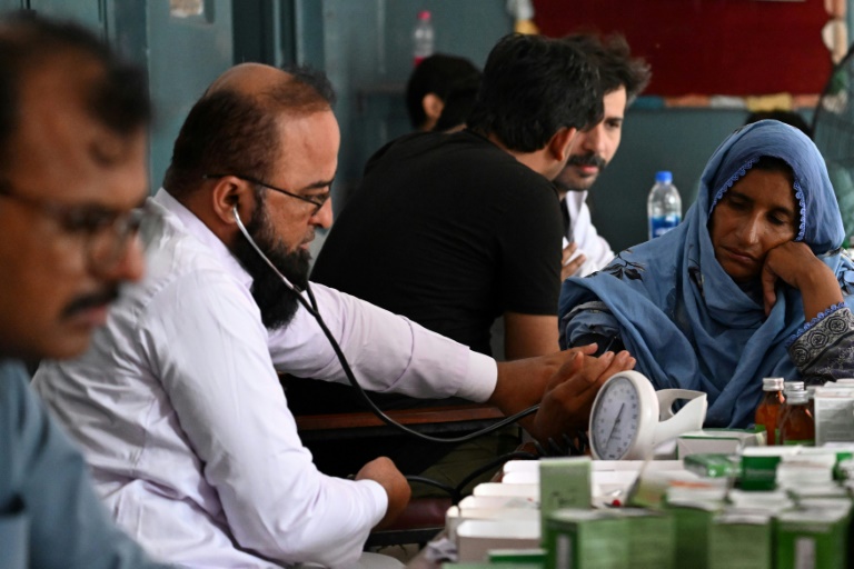 Un médecin examine une habitante évacuée de sa maison submergée par les eaux en crue du fleuve Ravi, dans une école publique transformée en refuge temporaire à Shahdara, le 29 août 2025 au Pakistan