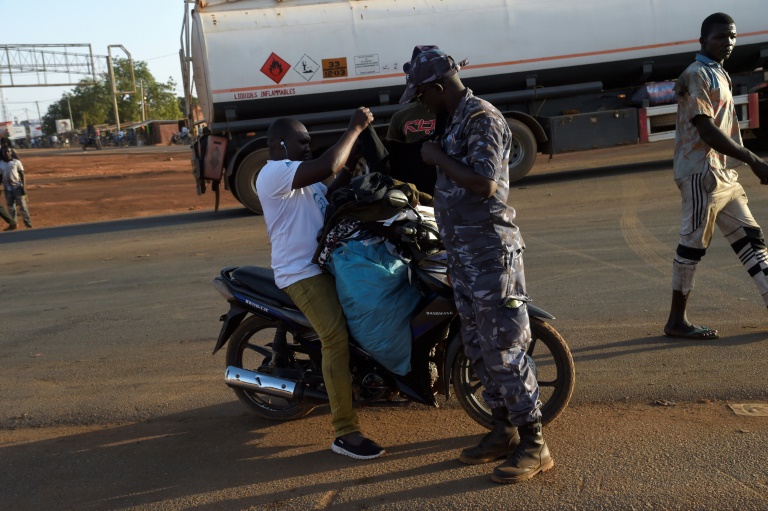 Un policier fouille un vendeur à moto à Cinkassé, un poste frontalier commercial du nord du Togo avec le Burkina Faso, le 16 février 2020