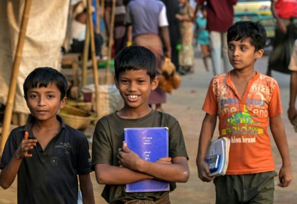 Des enfants réfugiés rohingyas portent leurs manuels scolaires au camp de réfugiés de Kutupalong, le 17 décembre 2025 à Ukhia, au Bangladesh