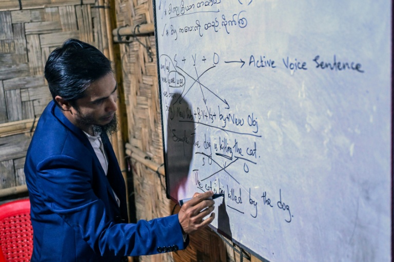 Mohammad Amin, réfugié rohingya et enseignant, donne un cours dans une salle de classe d'un centre éducatif de fortune au camp de réfugiés de Kutupalong, le 17 décembre 2025  à Ukhia, au Bangladesh