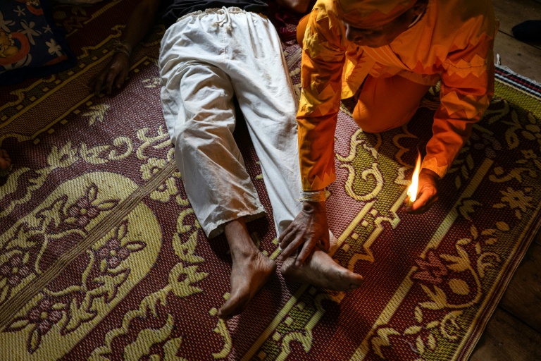 Photo fournie par Luke Duggleby, prise le 10 décembre 2025 et transmise à l'AFP le 25 février 2026, montrant le chef religieux Jaha Satae (c,d), procédant à une cérémonie de purification sur Jawa Jabo (chemise noire), dans le village de Mae Haeng, à Chiang Mai, en Thaïlande