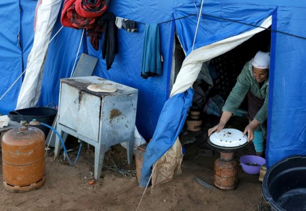 Une femme prépare à manger dans l'une des tentes d'un camp destiné aux personnes touchées par les inondations qui ont frappé le nord et l'ouest du Maroc, dans la région de Kénitra, le 20 février 2026