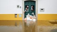 Deux religieuses observent la rue depuis une porte renforcée par des sacs de sable pendant les indondations liées à la tempête Leonardo à Alcacer do Sal, au sud du Portugal, le 4 février 2026