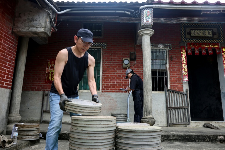 Un employé de l'Institut taïwanais du cinéma et de l'audiovisuel (TFAI) empile des bobines de vieux films taïwanais à restaurer issus d'une collection privée, le 29 mai 2026 à Changhua, dans la province de Taïwan
