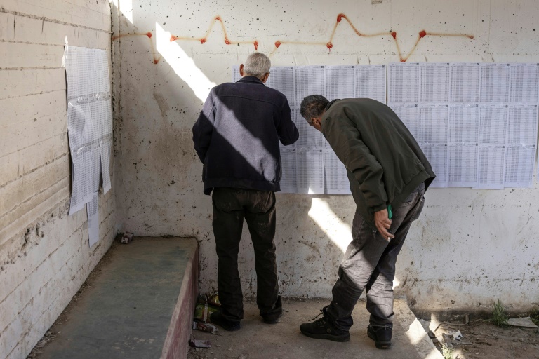 Deux hommes consultent les listes électorales dans un bureau de vote lors des élections municipales du village de Qabatiyah, au sud de Jénine, en Cisjordanie occupée par Israël, le 25 avril 2026