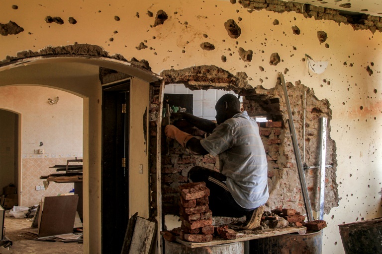 Un ouvrier du bâtiment travaille dans un appartement endommagé d'un un immeuble de la banlieue de Lambab, à la périphérie de Khartoum, le 30 juillet 2025 au Soudan