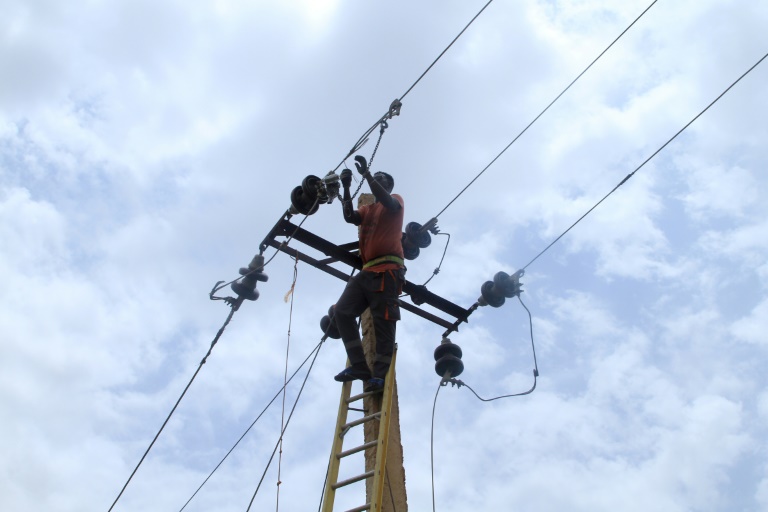 Un ouvrier municipal répare une ligne électrique à Khartoum le 4 août 2025 au Soudan