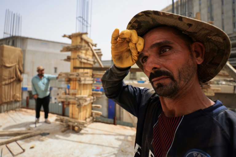 Un ouvrier sur un chantier de construction essuie la sueur de son front alors que les températures augmentent avec l'arrivée de l'été à Bagdad, le 28 mai 2025 en Irak