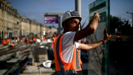 Un ouvrier travaillante sur un chantier de lignes de tramway le long de la Garonne se protège du soleil pendant une vague de chaleur à Bordeaux, dans le sud-ouest de la France, le 1er juillet 2025
