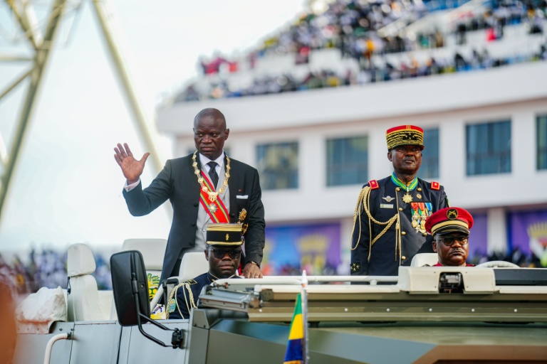 Le président du Gabon Brice Oligui Nguema (g) salue la foule au cours d'une cérémonie dans un stade de Libreville, le 3 mai 2025