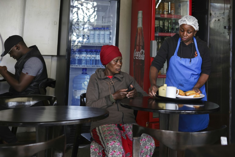 Margaret John (c) échange des points gagnés en livrant des déchets plastiques à un point de collecte de l'ONG Human Needs Project (HNP) contre un repas dans le bidonville de Kibera, à Nairobi, le 11 août 2025 au Kenya