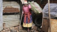 Molly Aluoch s'appuie sur une béquille pour porter un sac de déchets plastiques usagés collectés dans le bidonville de Kibera, à Nairobi, le 11 août 2025 au Kenya
