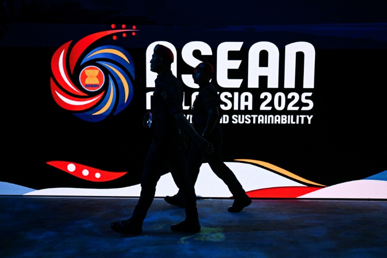Des membres de la police royale de Malaisie passent devant le logo du 47e sommet de l'Association des nations de l'Asie du Sud-Est (Asean), le 25 octobre 2025 à Kuala Lumpur.
