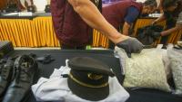 Des agents des douanes présentent l'uniforme d'un pilote ainsi que la drogue qu'il a fait passer en contrebande, lors d'une conférence de presse à l'aéroport international Soekarno-Hatta de Tangerang, près de Jakarta, le 31 juillet 2026 en Indonésie