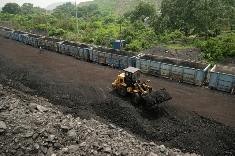 Un ouvrier transporte des tas de charbon brut dans des wagons de train, extraits d'une mine à ciel ouvert à la périphérie de Dhanbad, dans l'État indien du Jharkhand, le 13 août 2025