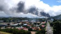 Un panache de fumée est visible au loin, alors que des émeutes ont lieu en Nouvelle-Calédonie en écho à une révision constitutionnelle examinée à l'Assemblée nationale, le 14 mai 2024 à Nouméa en Nouvelle-Calédonie