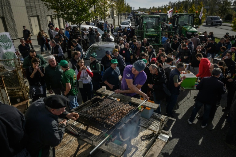 Des agriculteurs préparent un barbecue à Montaudran, près de Toulouse, le 12 novembre 2025, tandis que des membres de la FNSEA et de la Confédération paysanne manifestent contre la visite du président Emmanuel Macron et ses propos sur l'accord commercial du Mercosur