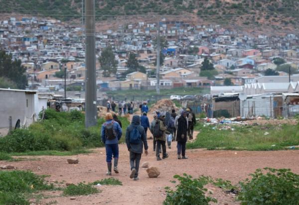 Des travailleurs, pour la plupart employés dans des fermes locales, rentrent chez eux à Nkqubela, un township et campement informel de la ville de Robertson (province du Cap-Occidental, Afrique du Sud), le 9 juillet 2026