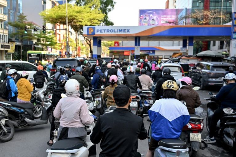 Des motocyclistes font la queue pour faire le plein d'essence dans une station-service à Hanoï, le 10 mars 2026 au Vietnam