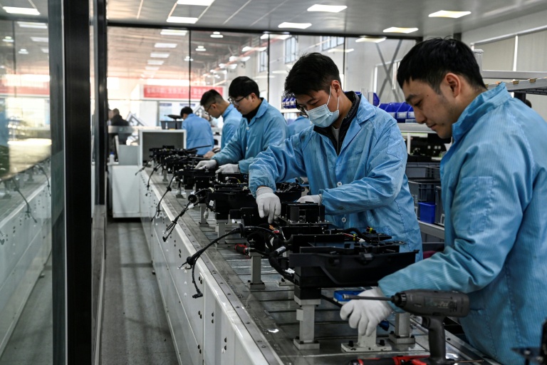 Des ouvriers travaillent sur une ligne de production de l'usine Neolix qui fabrique de petits véhicules utilitaires autonomes pour le transport de colis en ville, le 4 décembre 2025 à Yancheng dans la province chinoise du Jiangsu 