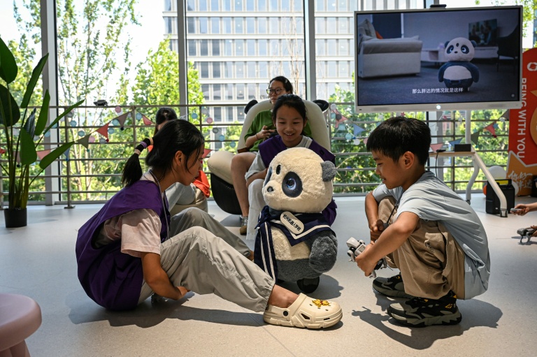 Des enfants jouent avec le robot Pangda à l'école des robots de Hangzhou, dans la province du Zhejiang, le 4 août 2026 dans l'est de la Chine