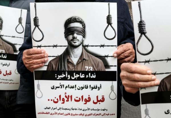 Des manifestants brandissent des pancartes sur lesquelles on peut lire "Appel urgent et final : arrêtez l'application de la loi sur les prisonniers avant qu'il ne soit trop tard" devant les locaux de la Croix-Rouge à Ramallah, en Cisjordanie occupée par Israël, le 31 mars 2026