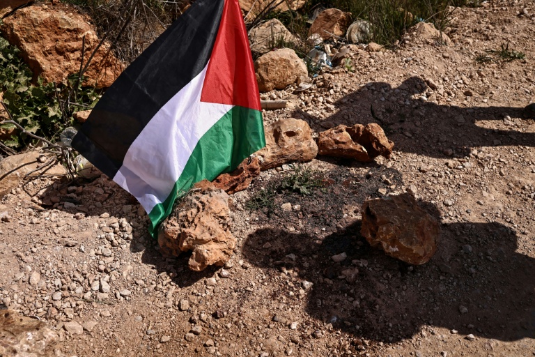 Un drapeau palestinien sur les lieux d'une attaque de colons israéliens qui a coûté la vie à plusieurs Palestiniens dans le village de Abou Falah, au nord-est de Ramallah, le 12 mars 2026