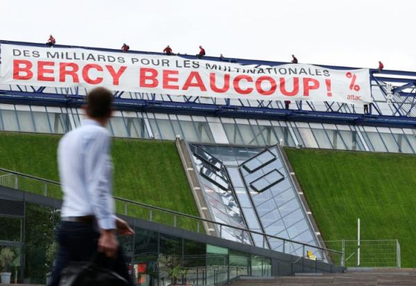 Des militants de l'organisation Attac France déploient une banderole sur la salle de spectacles Accor Arena à Paris mardi 2 juin 2026, protestant contre les aides publiques aux multinatinales 