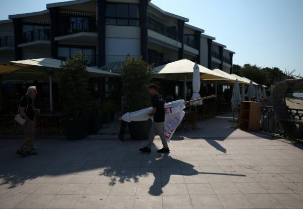 Un employé de restaurant transporte un parasol à Andernos-les-Bains, en Gironde, le 1er août 2026
