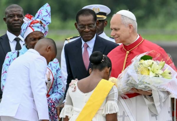 Le pape Léon XIV (à droite) reçoit des fleurs d'enfants alors qu'il est accueilli par le président de Guinée équatoriale Teodoro Obiang Nguema Mbasogo (au centre) à son arrivée à l'aéroport international de Malabo à Malabo le neuvième jour d'un voyage apostolique de 11 jours en Afrique, le 21 avril 2026.
