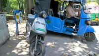 Un conducteur de rickshaw recharge son véhicule à côté d'un scooter électrique, à New Delhi, en Inde, le 12 avril 2026