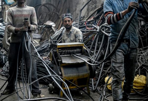 Des hommes récupérant de l'aluminium de fils plastiques dans un centre informel de recyclage de Seelampur, à New Delhi en Inde, le 28 janvier 2026